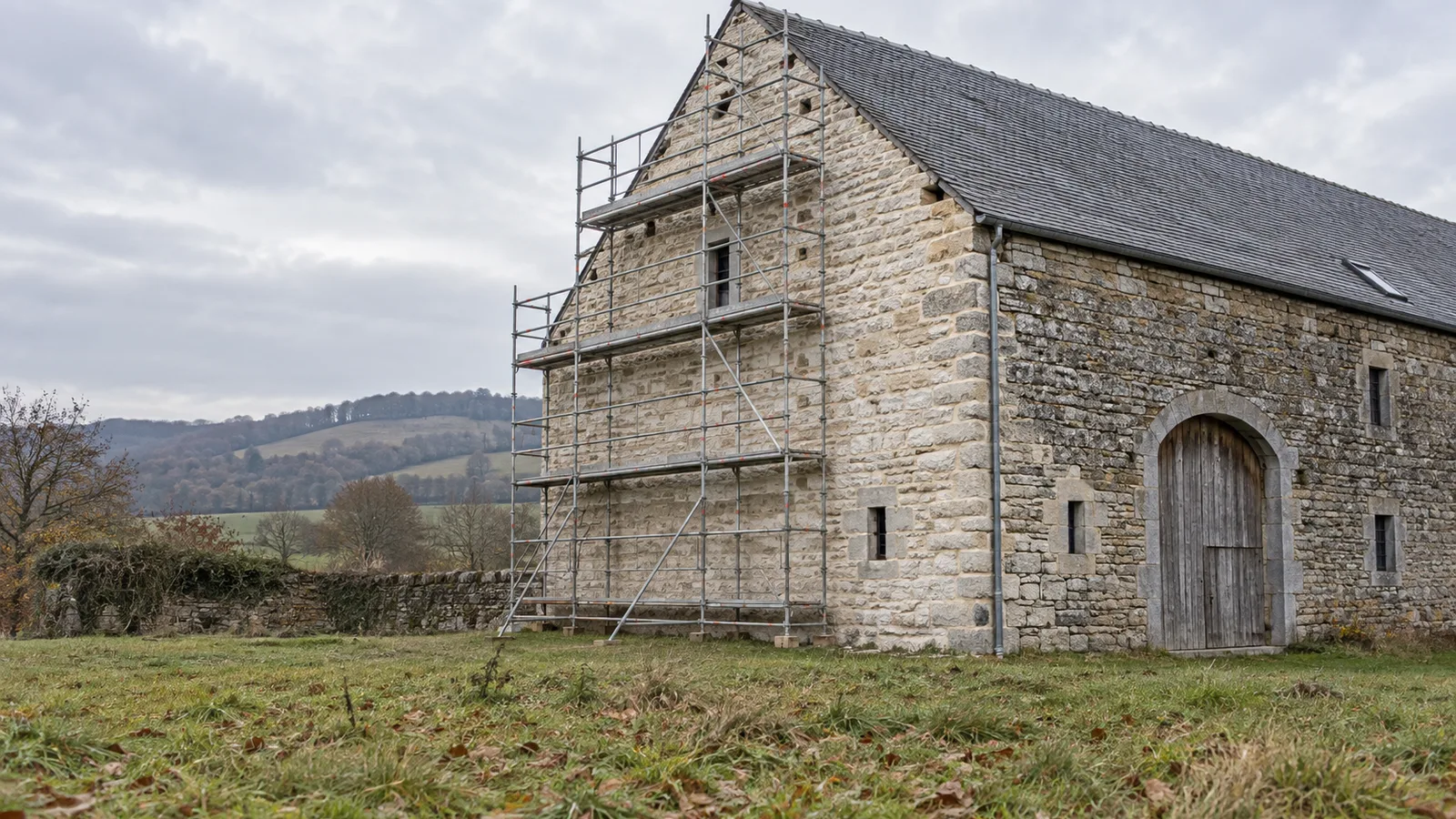 Grange en pierre avec échafaudage et joints de chaux à moitié refaits